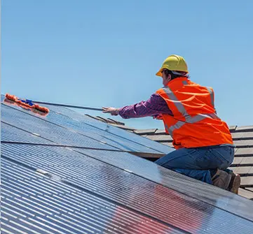 A man in an orange vest is working on solar panels.