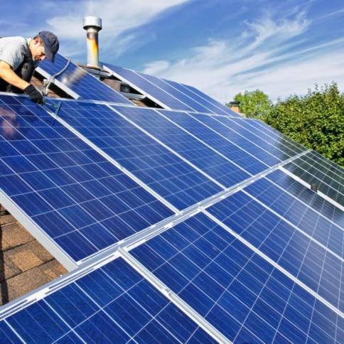 A man working on solar panels on the roof of a house.