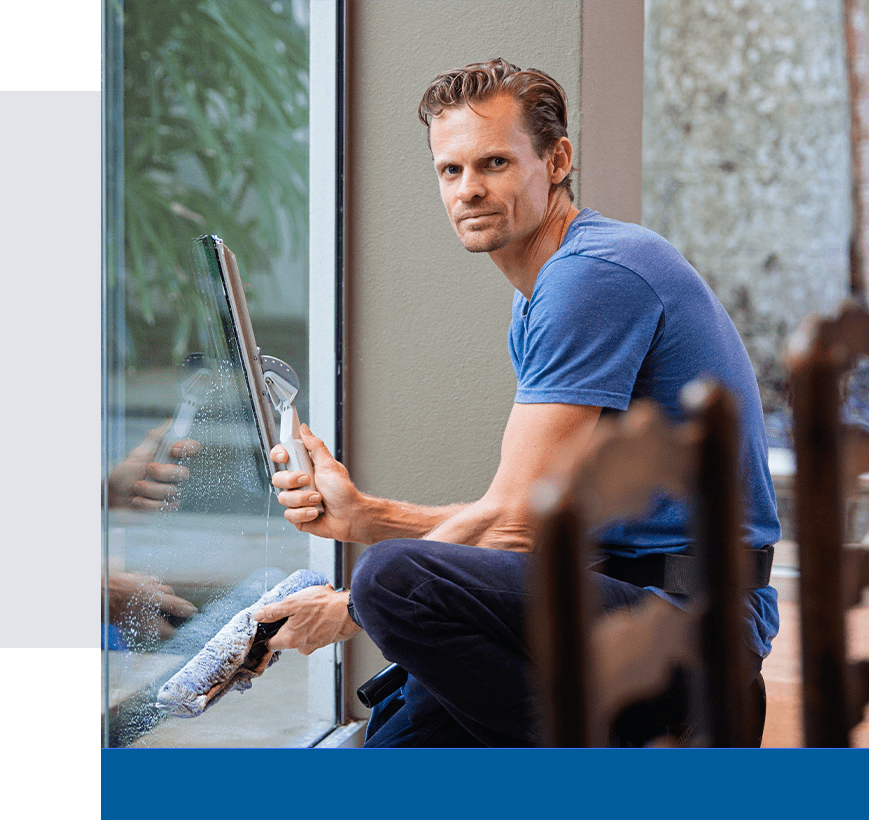 A man sitting on the ground holding a window glass.